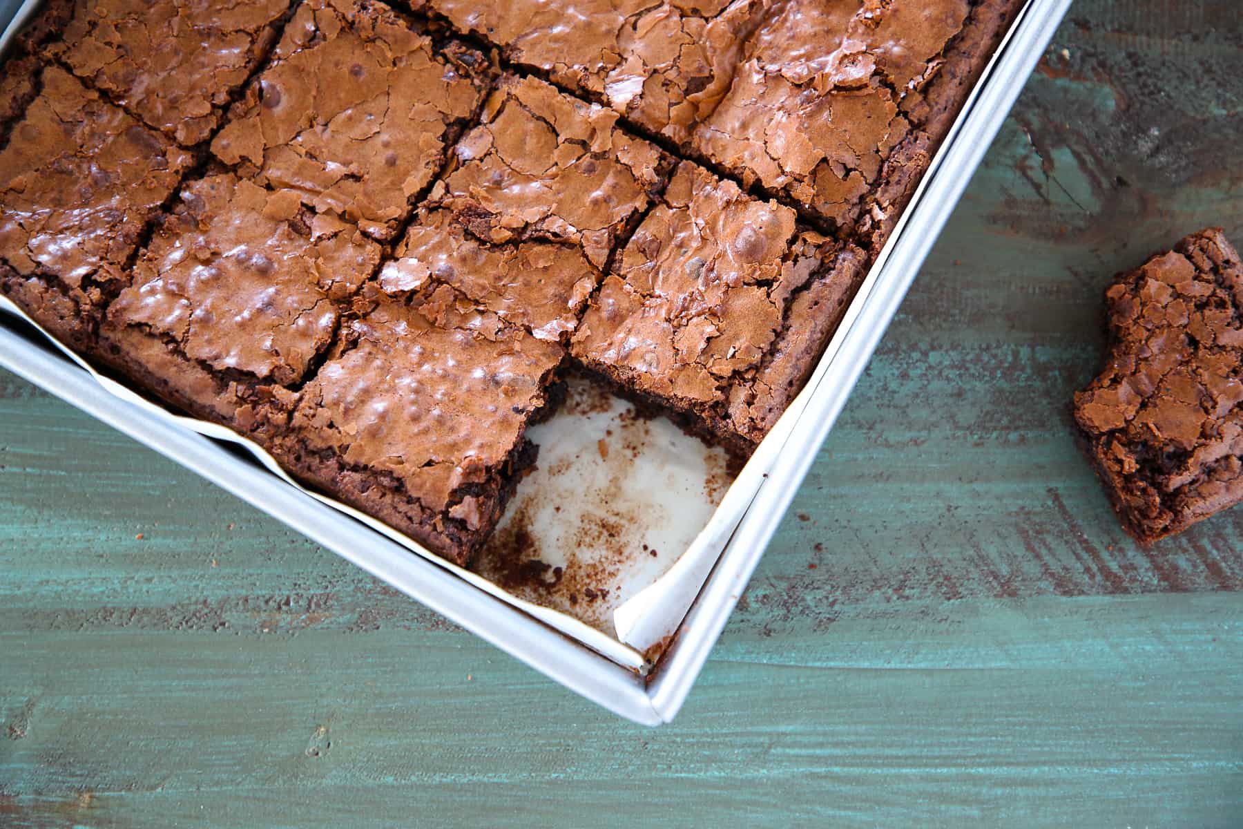 Freshly baked fudgy brownies resting in a metal pan, already to cut into squares.
