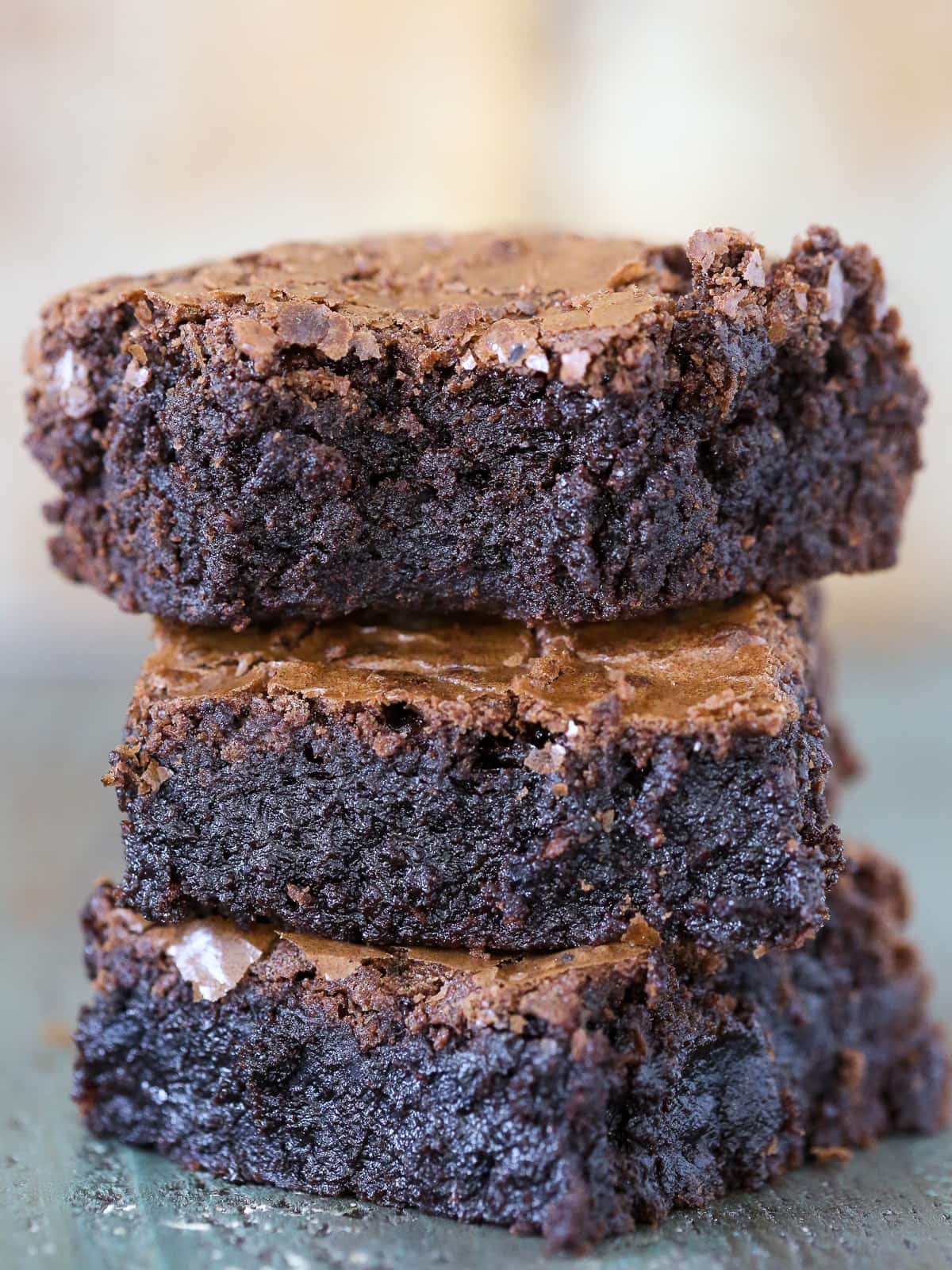 A small stack of gooey brownies revealing deep chocolate color and soft texture between layers.