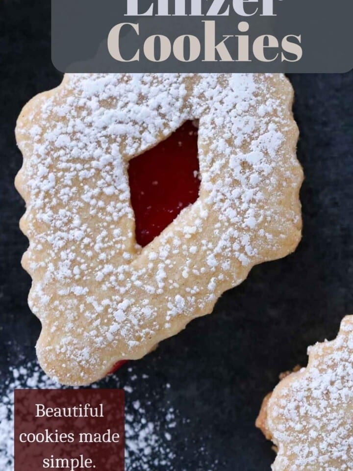 Buttery sandwich cookies with raspberry preserves on countertop, dusted with powdered sugar on top.