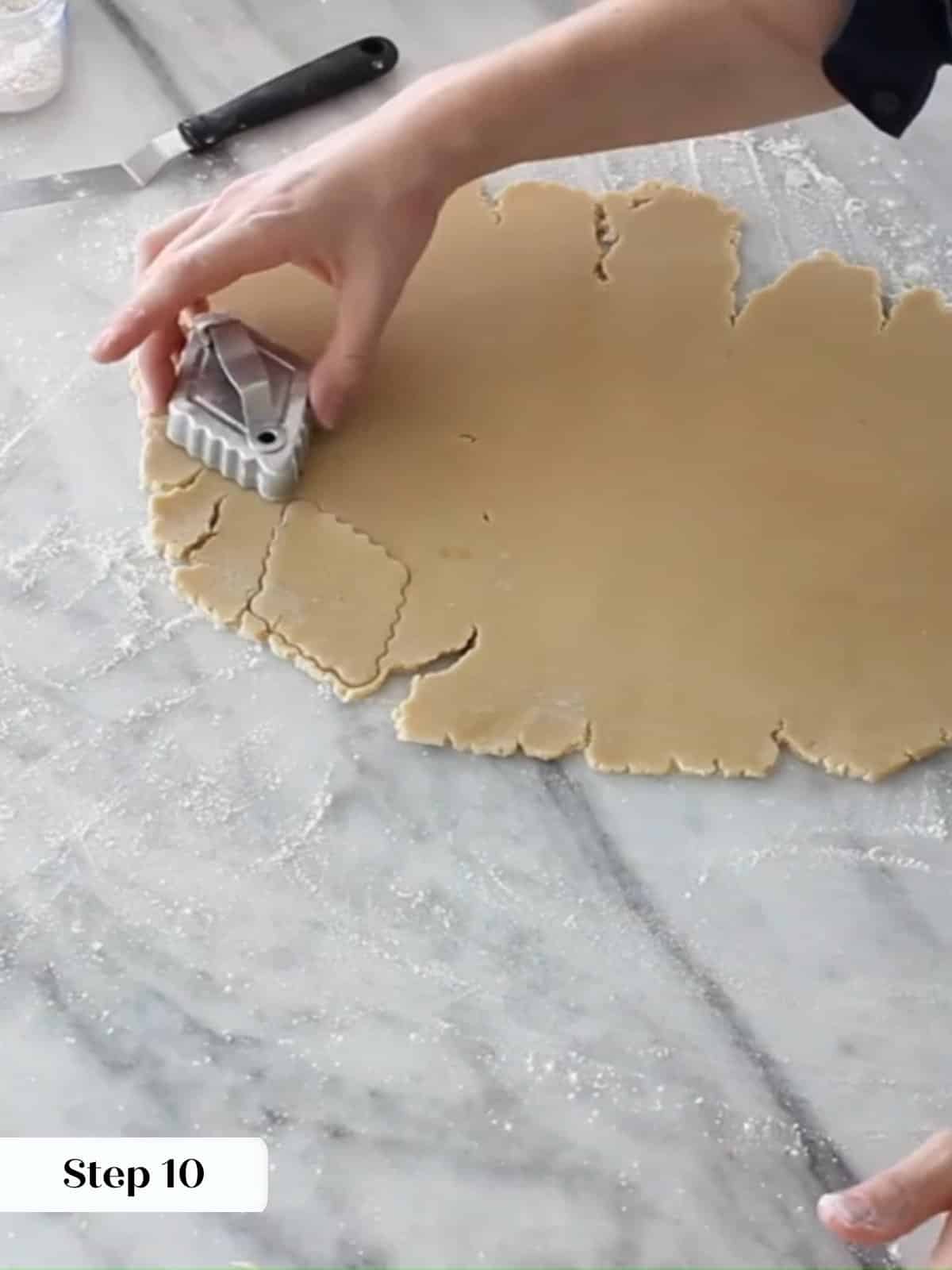 Freshly rolled Linzer dough being cut into even diamonds with a metal cookie cutter.