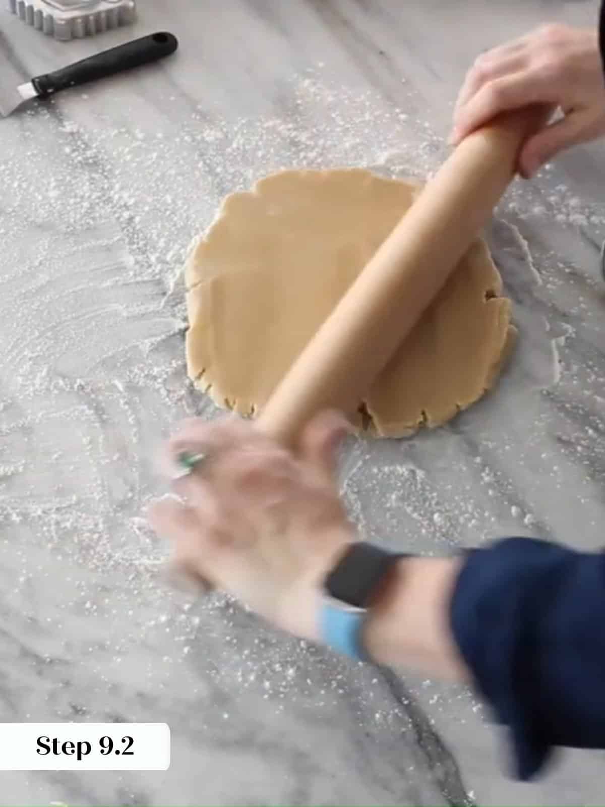 Cookie dough rolled thin with a wooden rolling pin on a lightly floured work surface.
