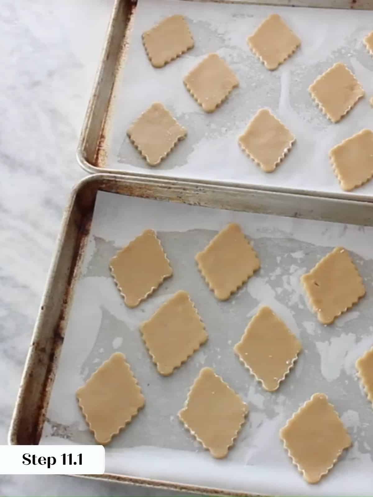 Unbaked Linzer cookie diamonds evenly spaced on a baking sheet lined with parchment paper.