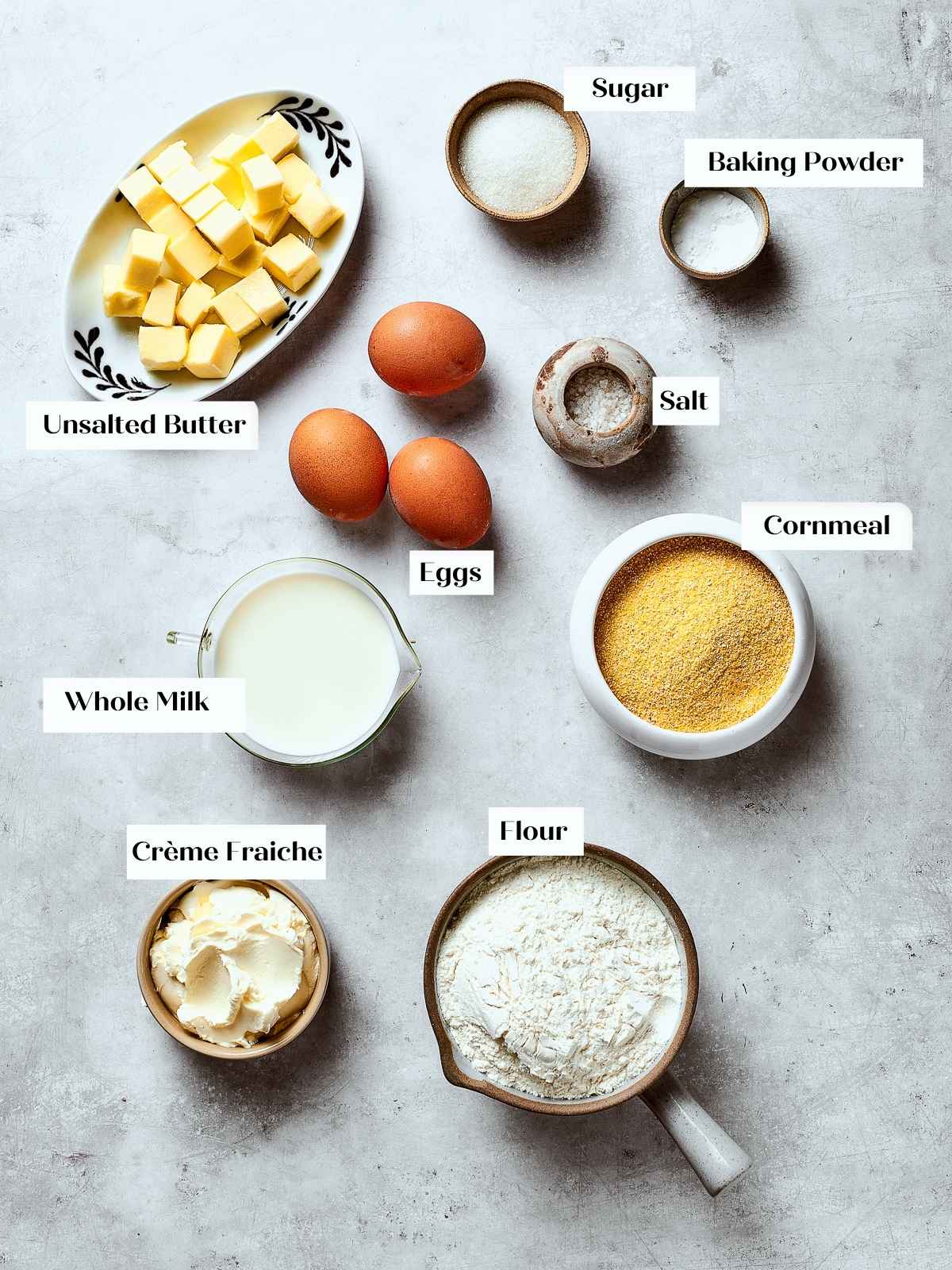 Cornbread ingredients including flour, cornmeal, milk, and eggs arranged on a kitchen counter.