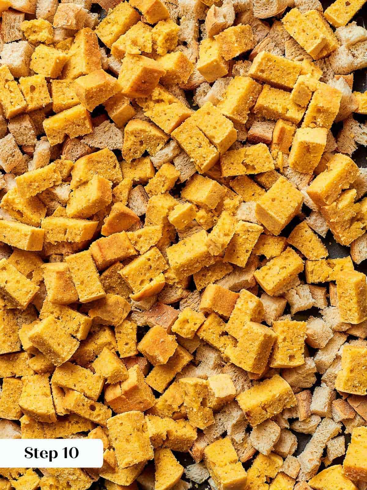 Cubes of cornbread and rustic bread spread on a baking sheet to dry overnight.