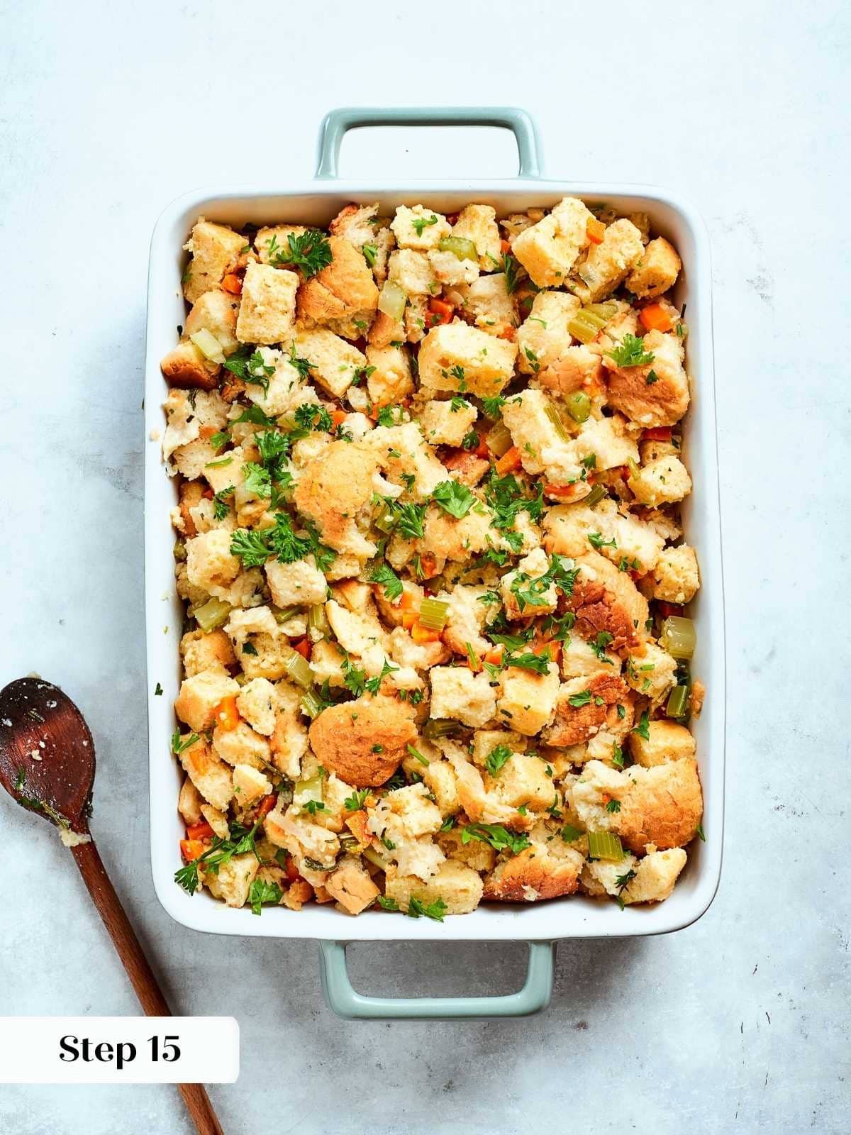 Cornbread stuffing mixture with vegetables and herbs arranged evenly in a baking dish ready to bake.