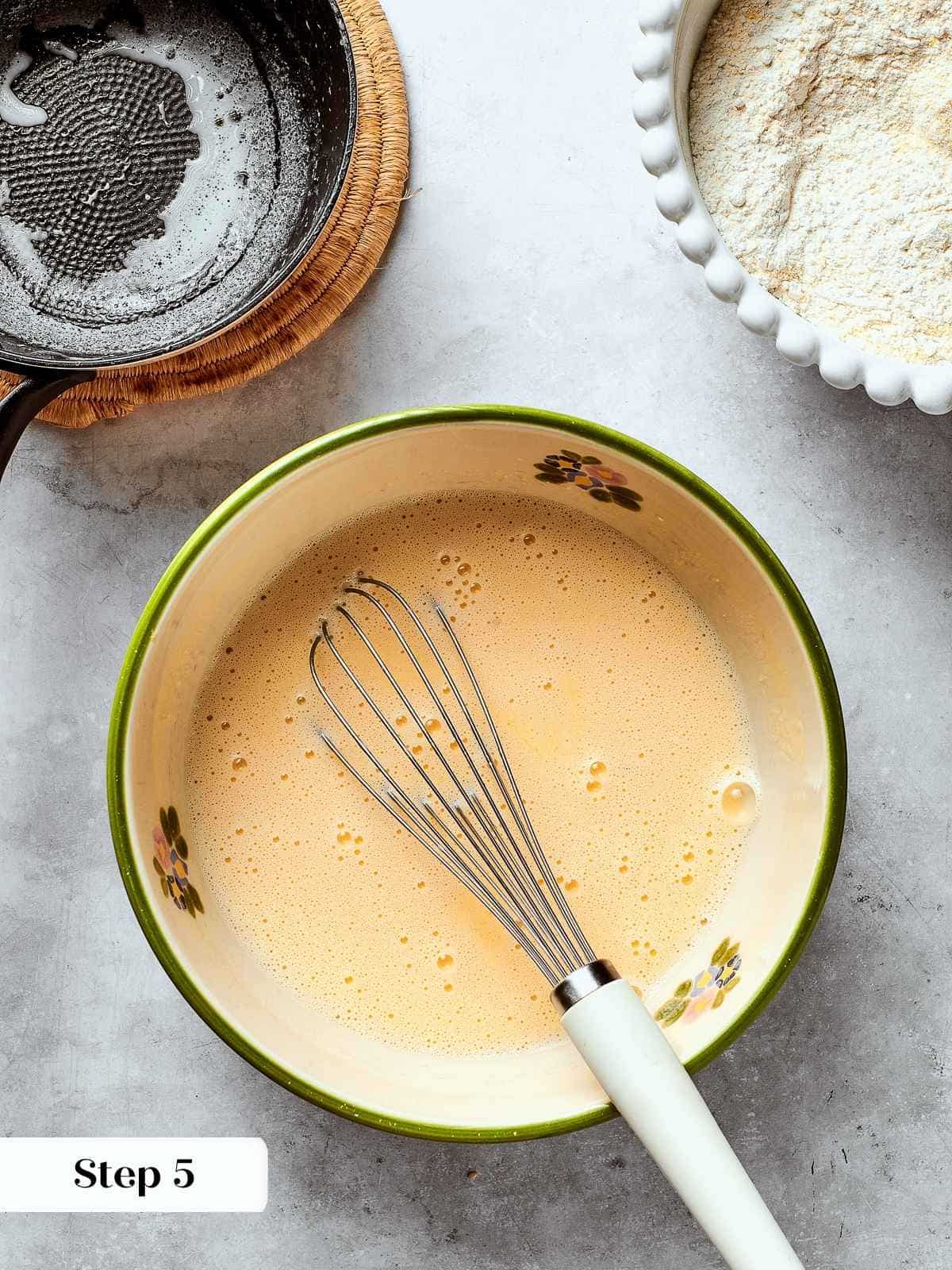 Combining milk and eggs together in a bowl to prepare the wet mixture for cornbread.