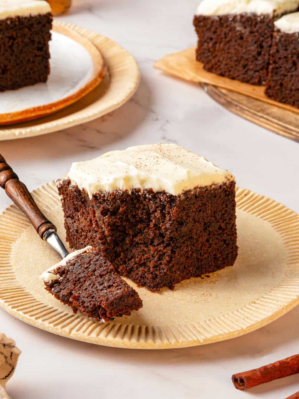 Fork holding a bite of gingerbread cake on the plate to show texture clearly.