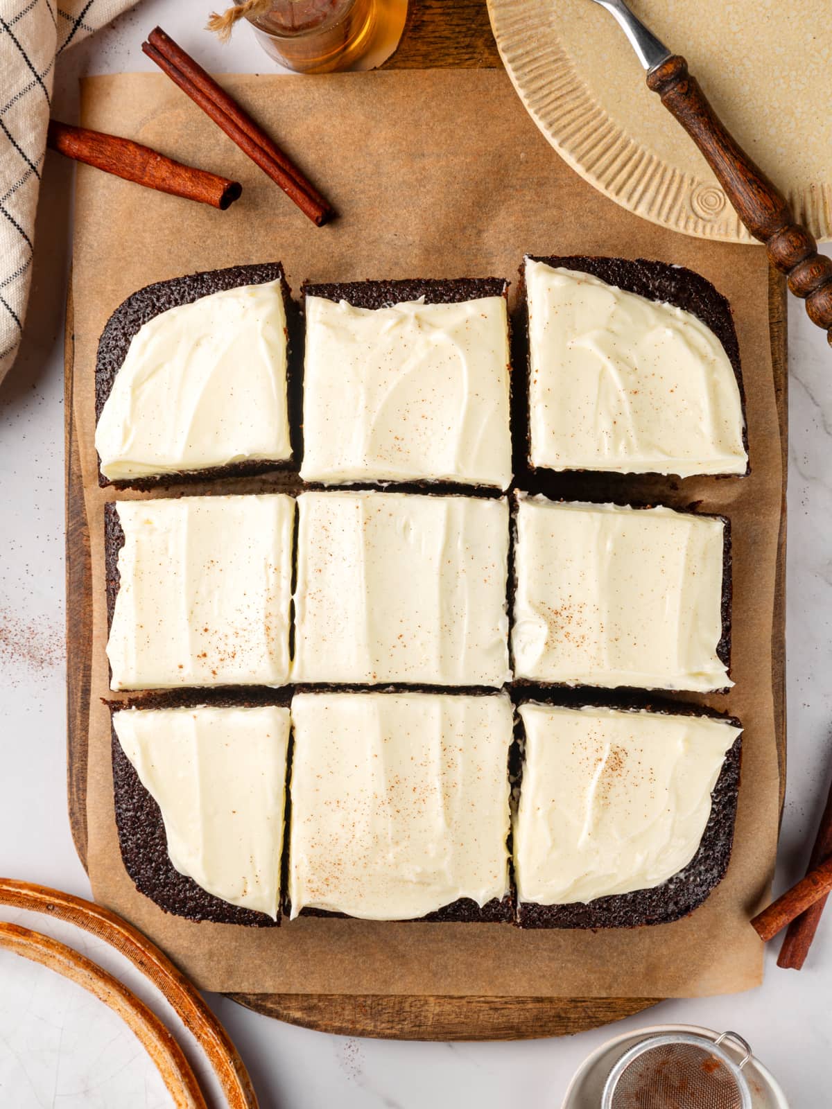 Frosted gingerbread cake cut into squares with creamy topping spread evenly across the surface.