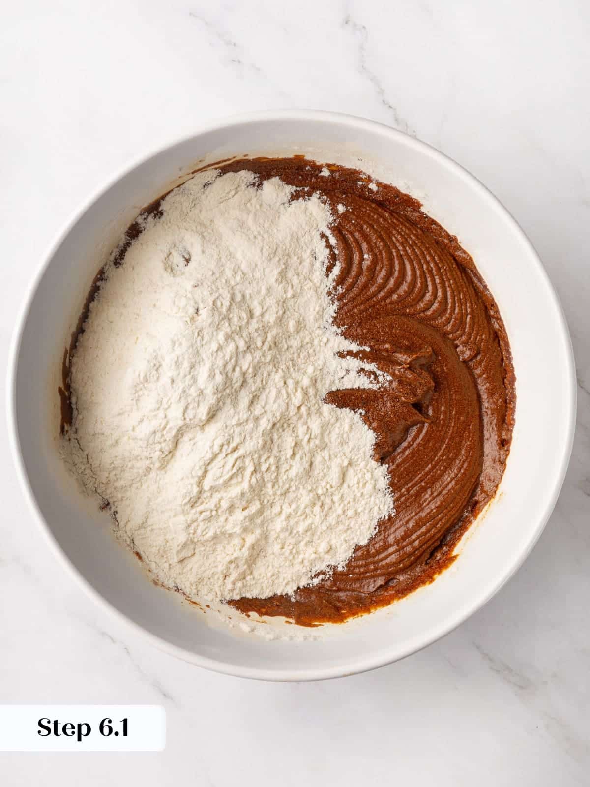 Spiced flour mixture being added into the wet gingerbread batter during mixing.