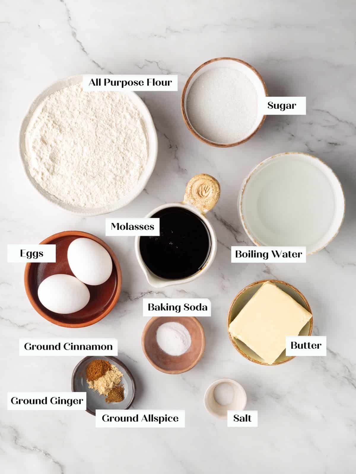 Butter, flour, spices, molasses, and eggs laid out for making homemade gingerbread cake.