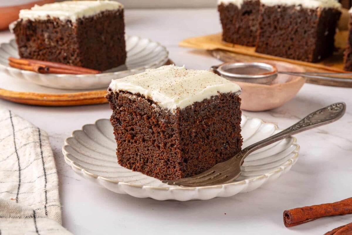 Single gingerbread cake square on a small plate highlighting fluffy interior and dark brown crumb.
