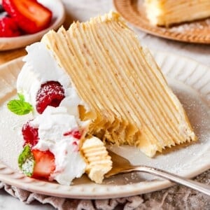 A lifted bite of crepe cake featuring soft creamy layers and a smooth vanilla texture.