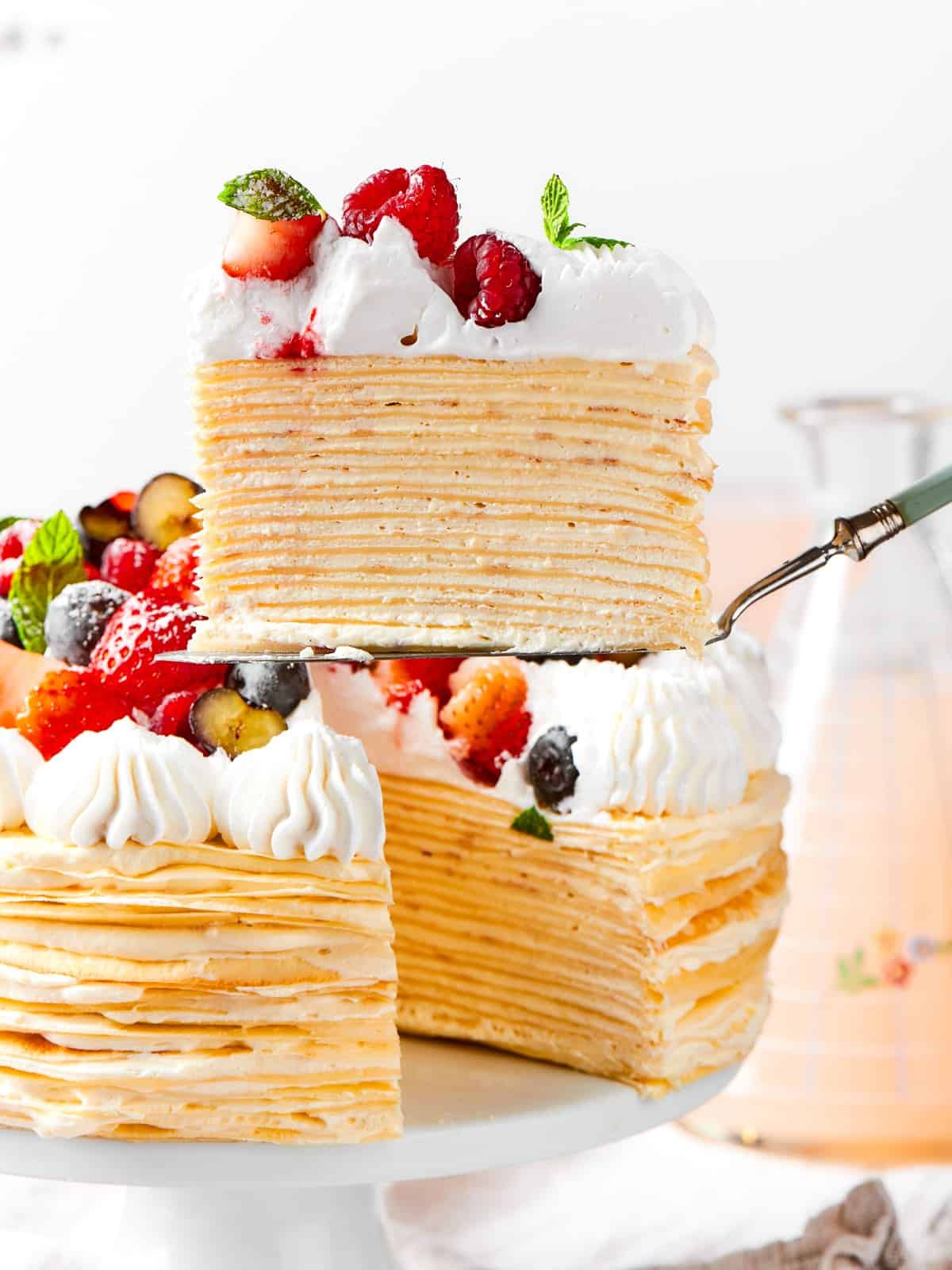The cake reveals its layered crepes and vanilla cream after a slice has been taken out.