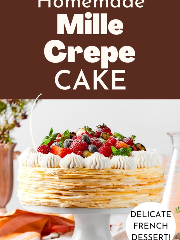 A tall vanilla mille crêpe cake layered with soft cream and fresh berries on top.