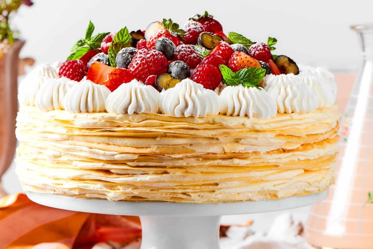 A full crepe cake decorated with fruit and creamy topping ready for the table.