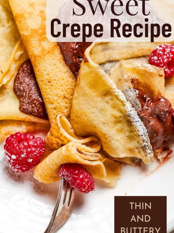 Warm sweet crepes sprinkled with sugar and served beside fresh raspberries and nutella.