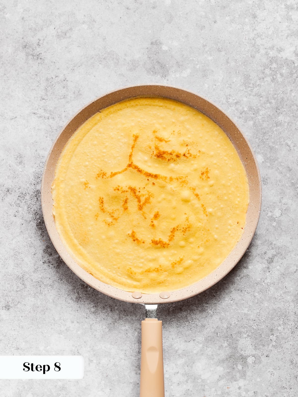 Freshly flipped crepe revealing a warm golden hue and delicate texture in the skillet.