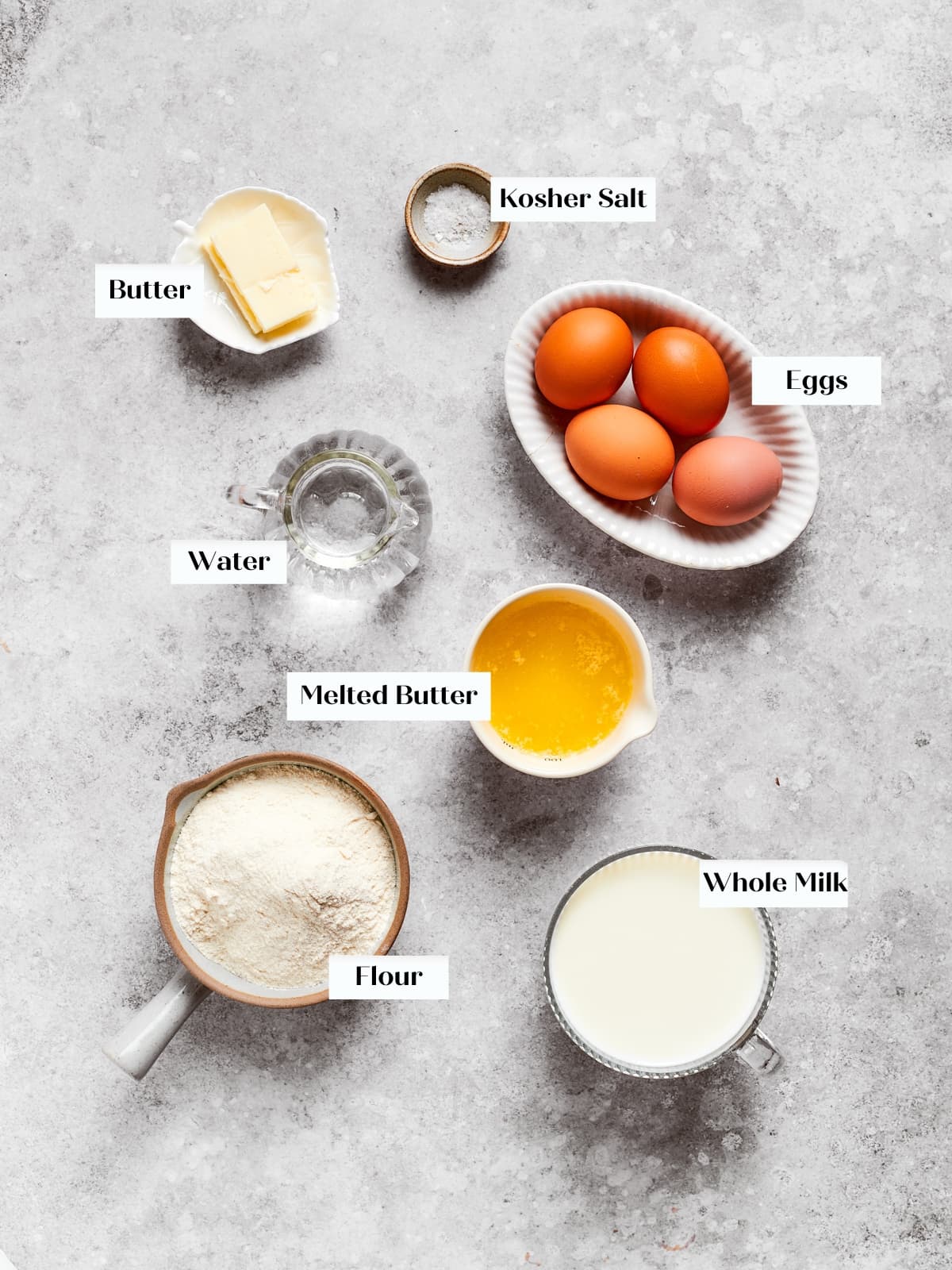 Eggs, flour, milk, and butter arranged on a countertop before mixing the crepe batter.