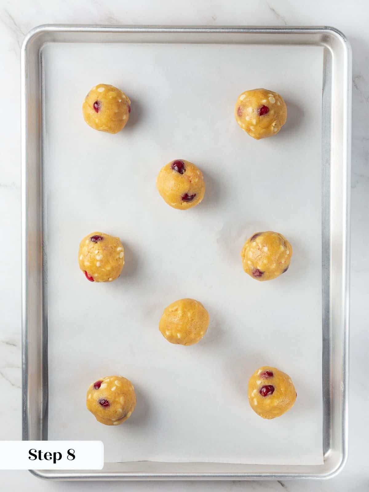 Scooped dough balls studded with cranberries and white chocolate before baking.