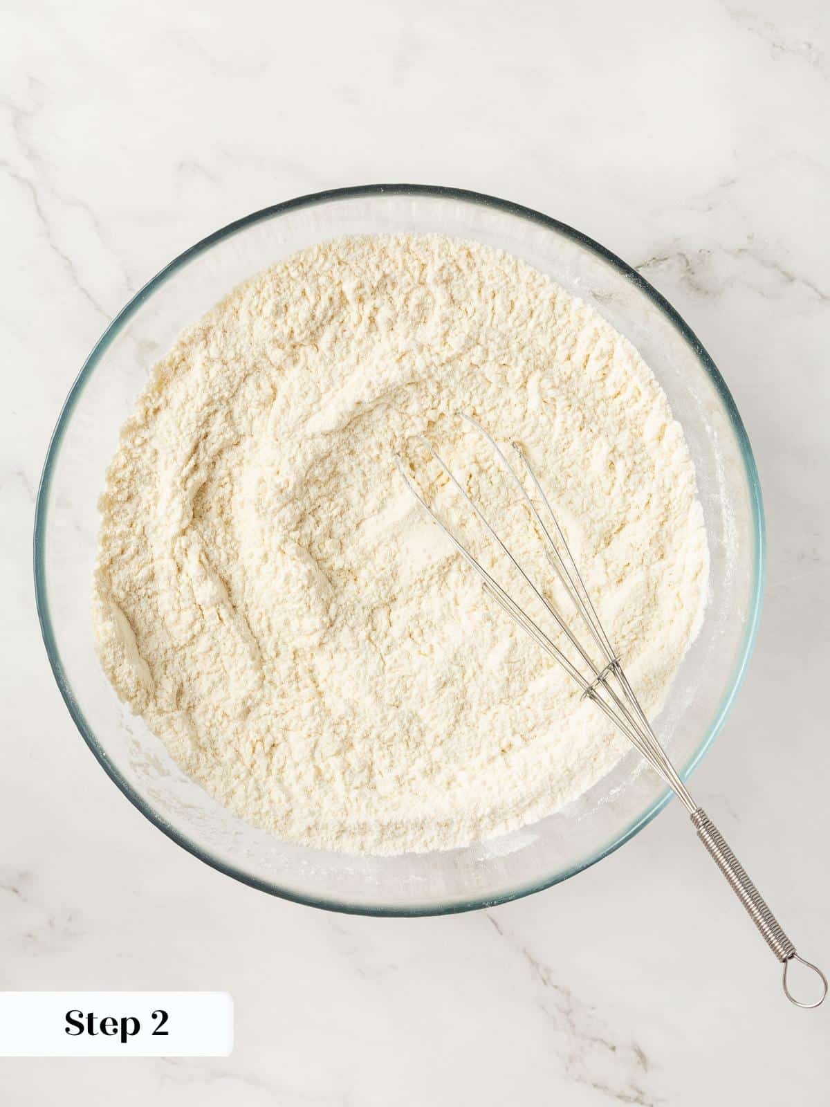 Dry ingredients for cranberry cookies being whisked together in a large mixing bowl.