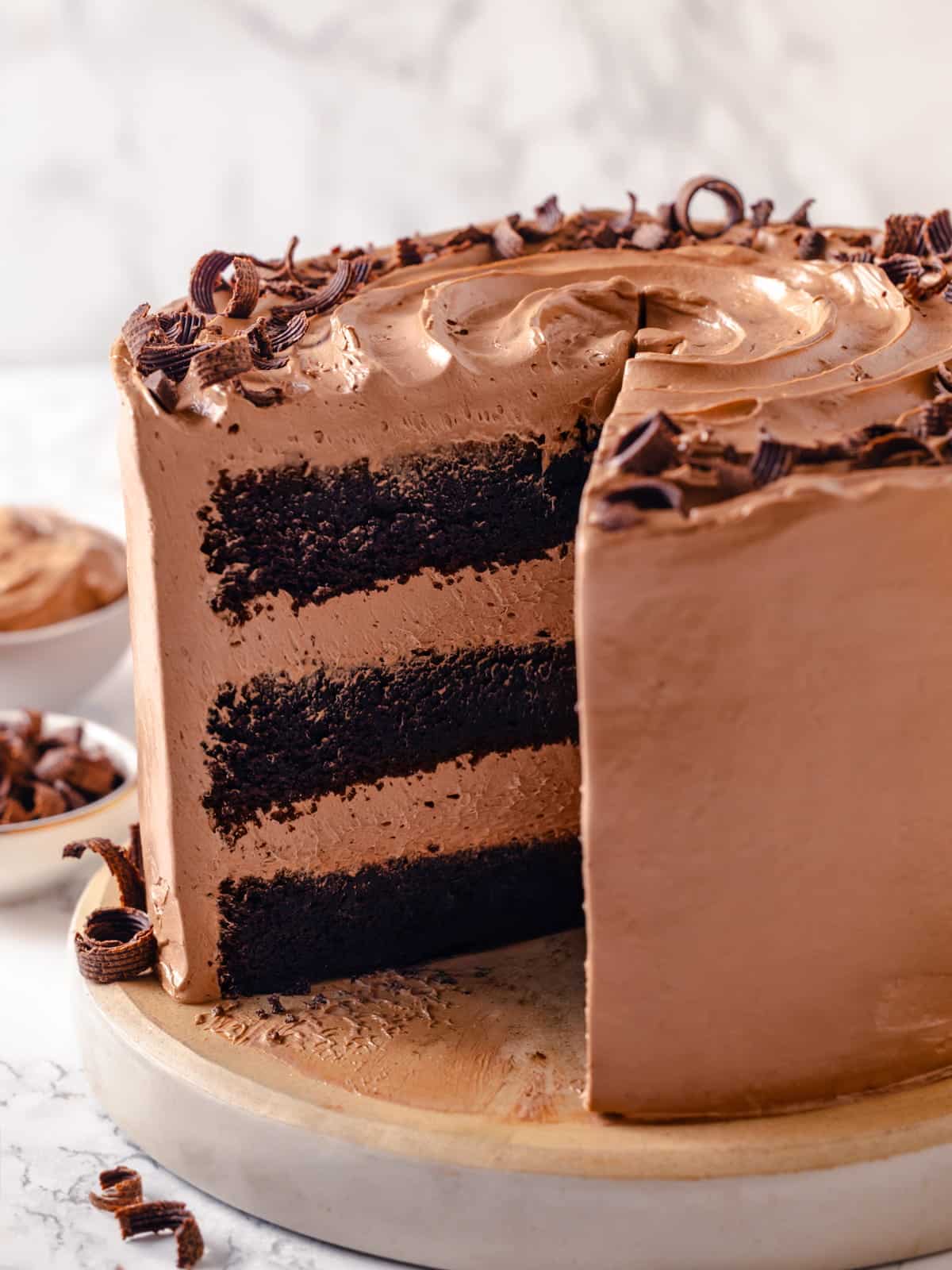 A frosted chocolate cake showing a missing slice and soft buttercream covering every side.