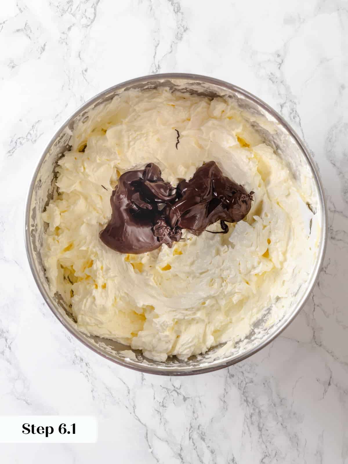 A bowl of buttercream ready as warm melted chocolate is added for final mixing.