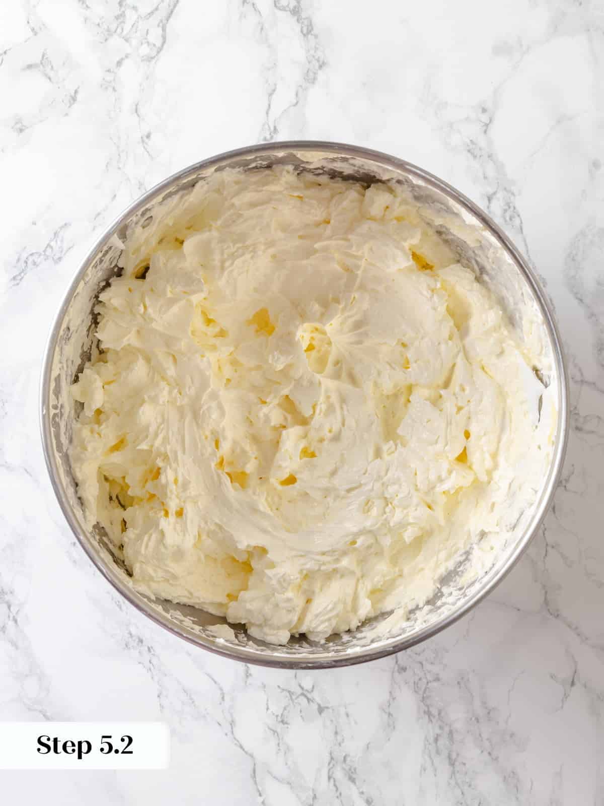 Butter slowly blending into whipped meringue inside a stand mixer for buttercream.