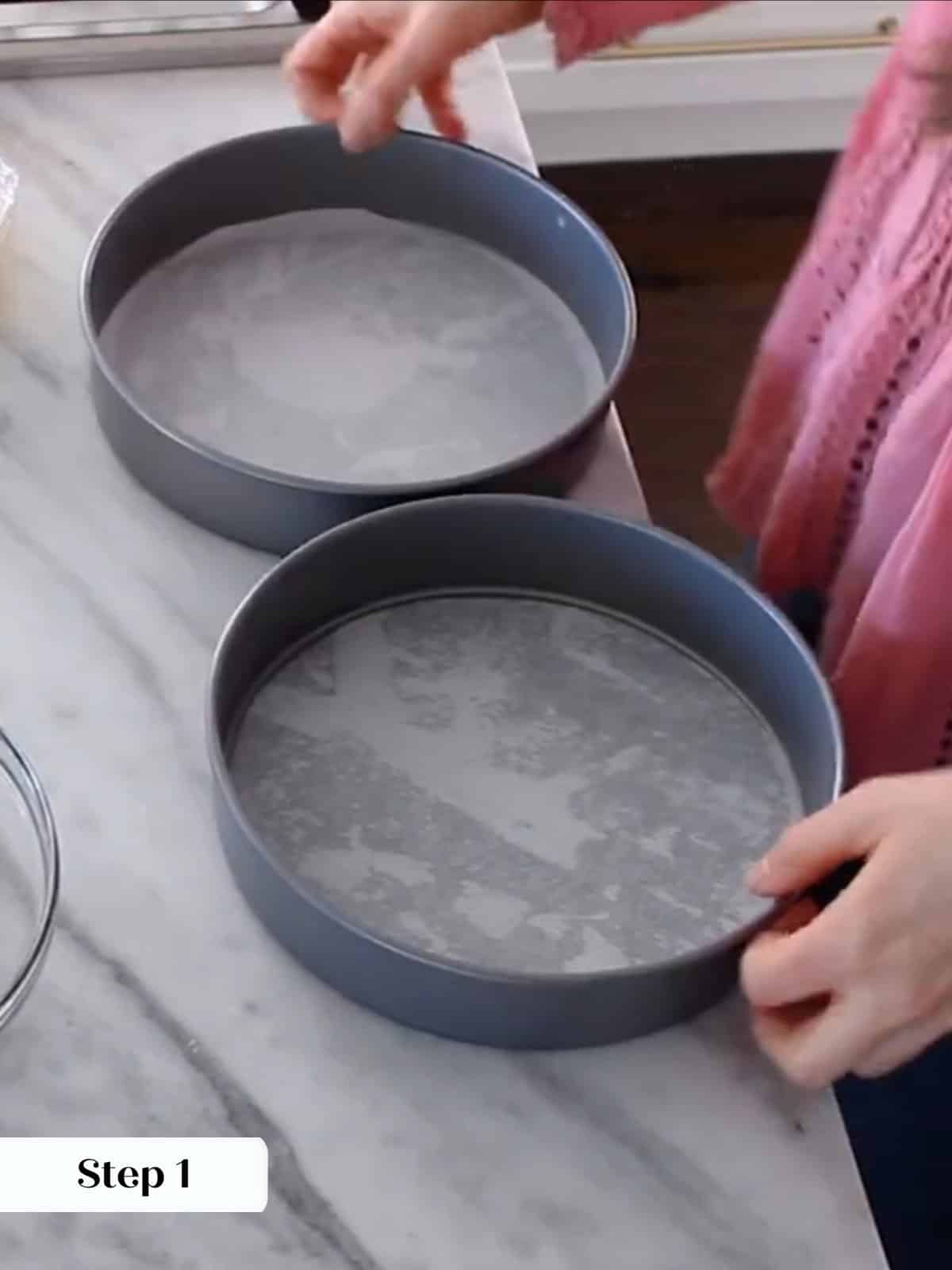 Prepared cake pans lined with parchment paper, ready for moist yellow cake batter.