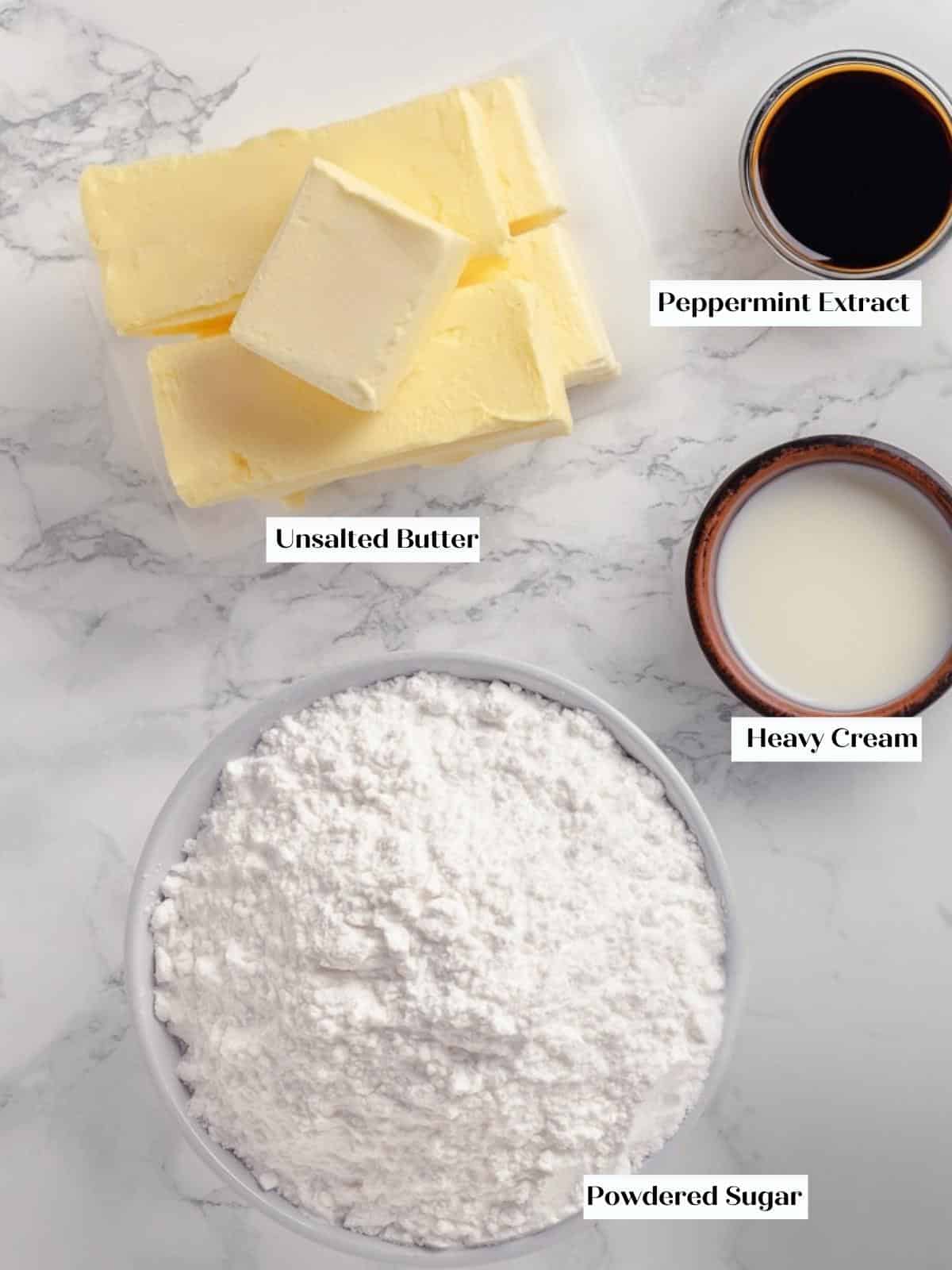 Butter, powdered sugar, peppermint extract, and cream arranged for making peppermint buttercream.