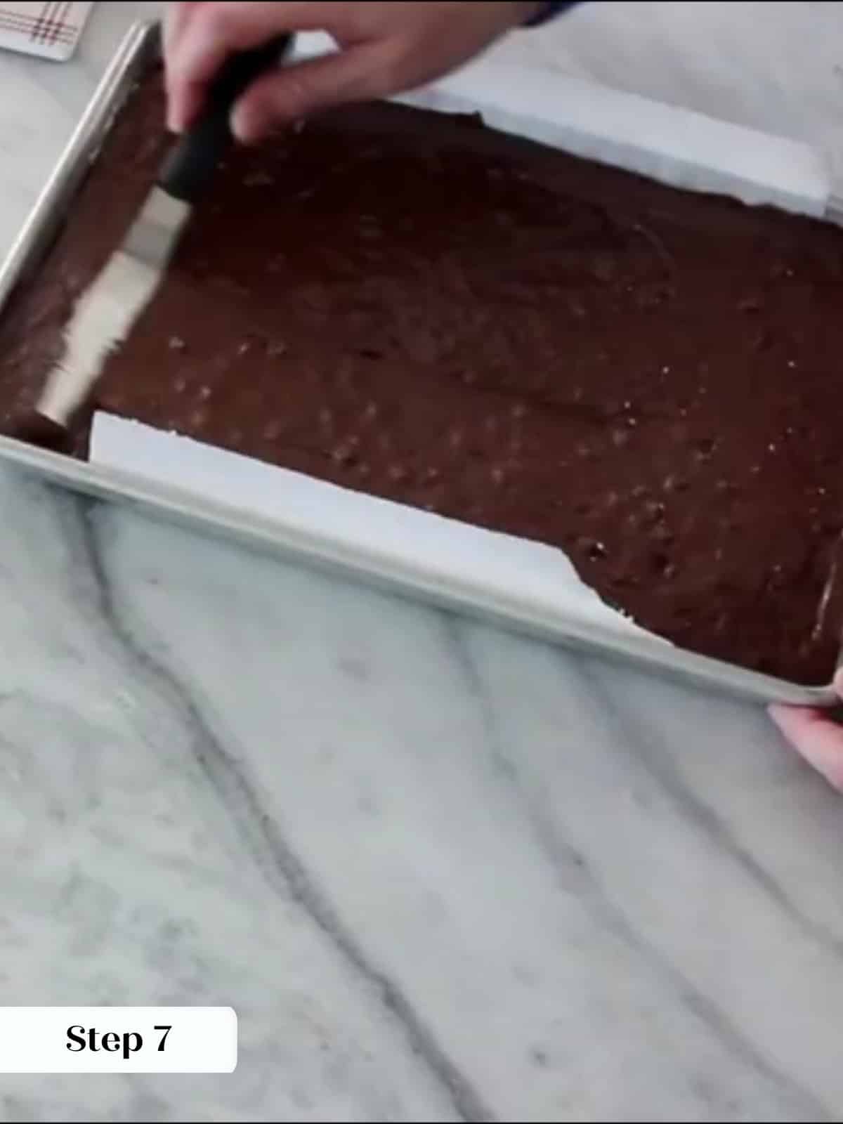 Thick brownie batter spread evenly into prepared pan using an offset spatula.
