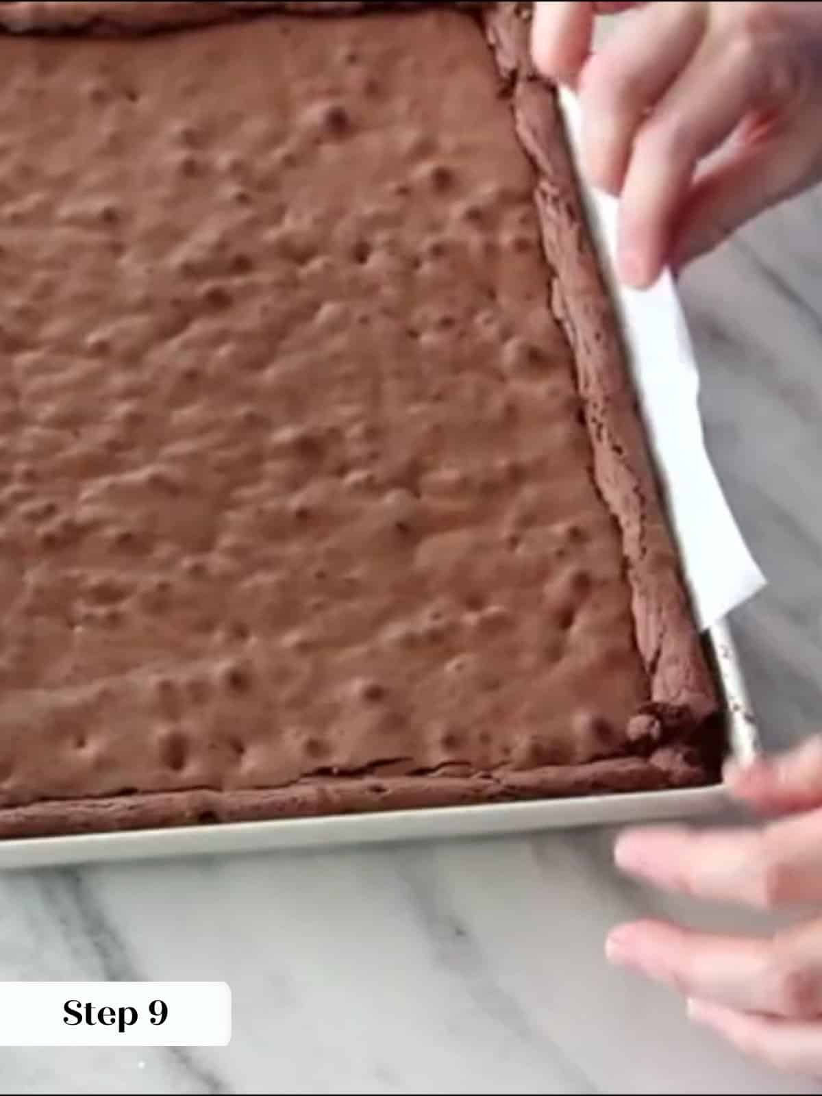 Cooled brownies lifted cleanly from pan using parchment paper handles.