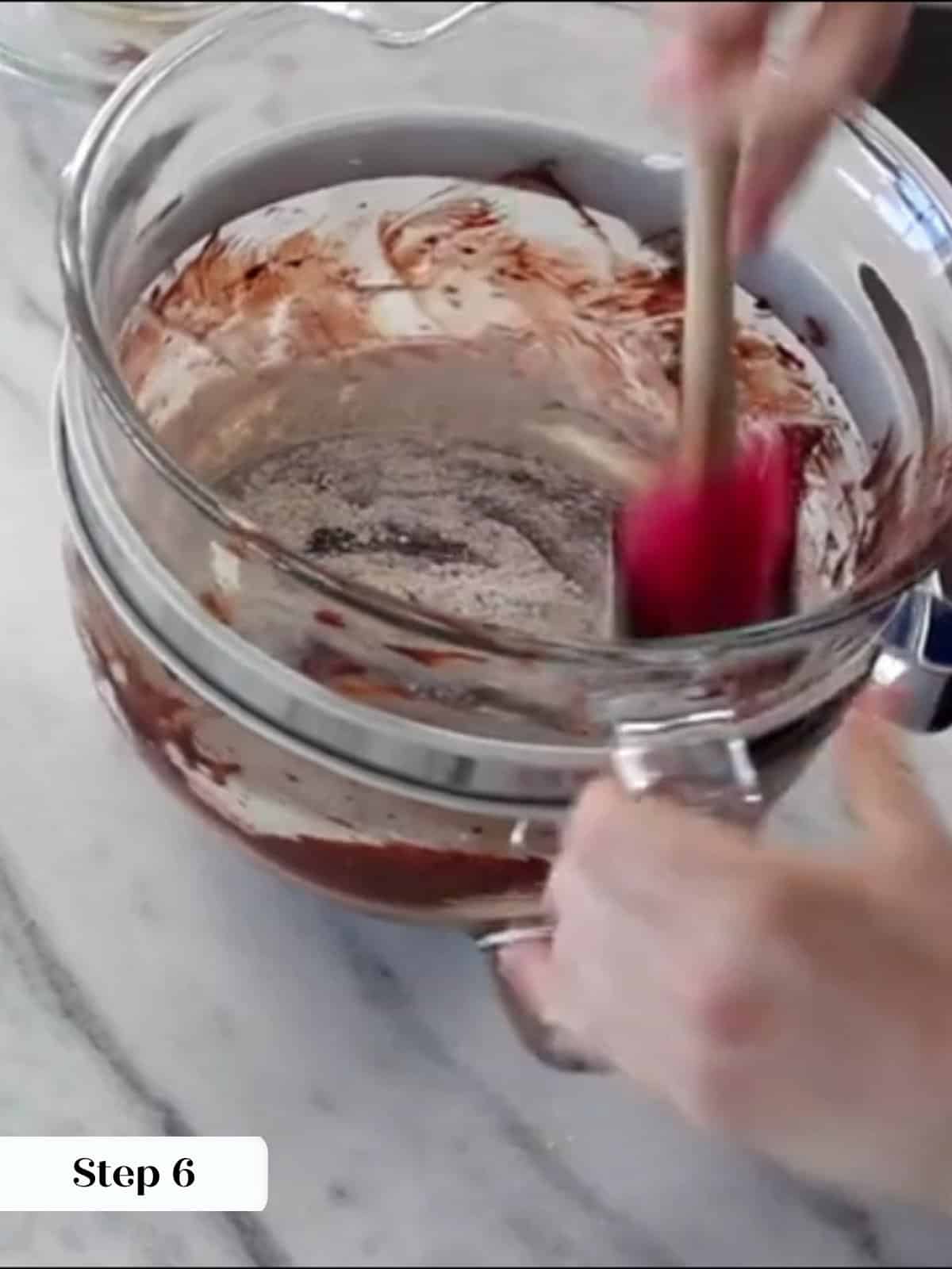 Flour mixture being folded carefully into brownie batter until just combined.