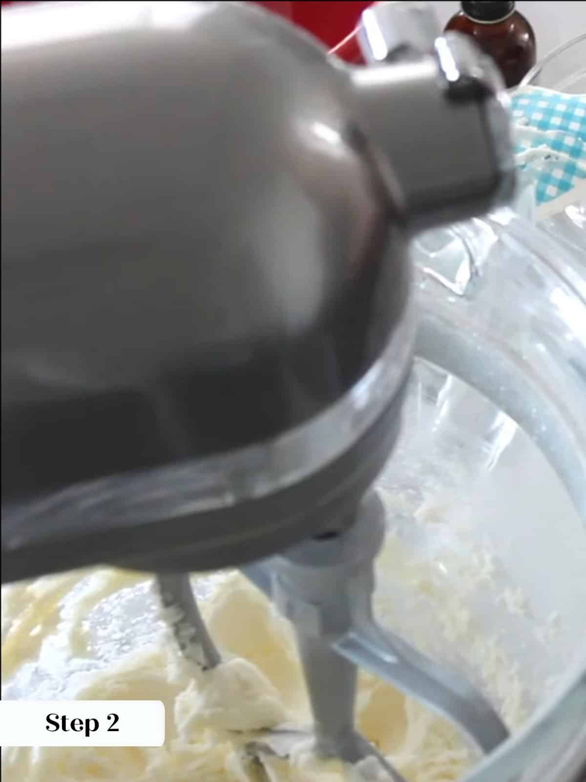 Butter and powdered sugar beating together in mixer bowl, forming base for peppermint frosting.