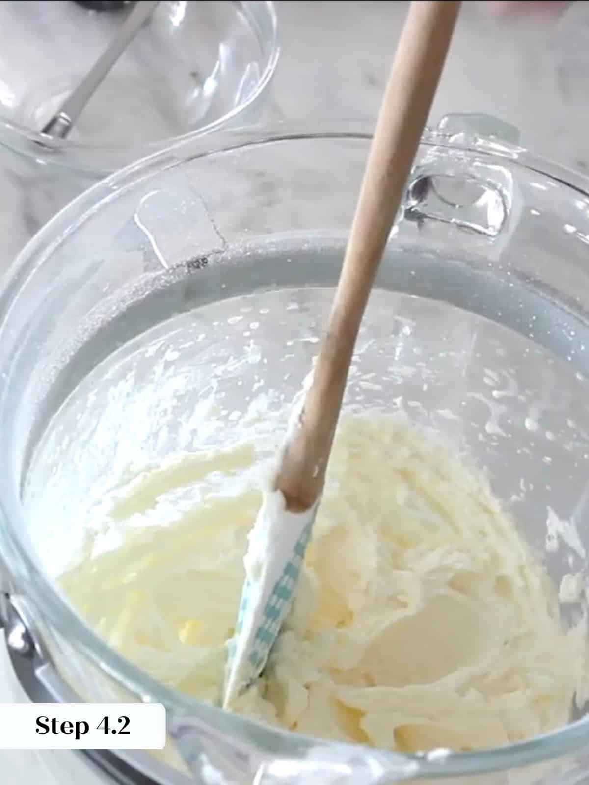 Peppermint frosting being scraped with a rubber spatula, showing smooth consistency during mixing.
