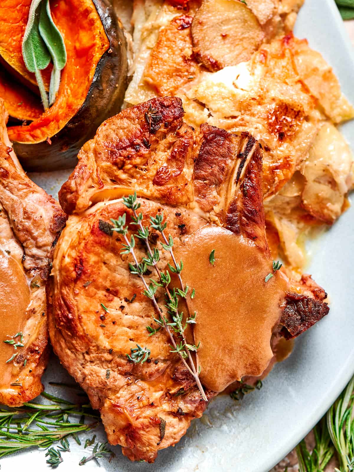 Pork chop topped with smooth applesauce sauce and fresh thyme leaves.