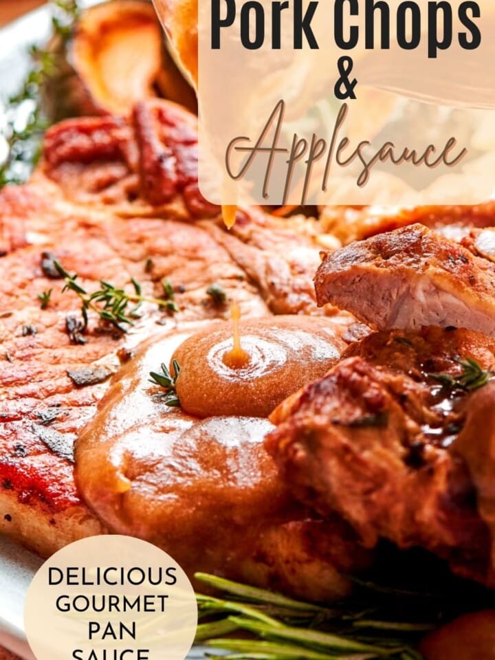 Pan-seared pork chops served with warm applesauce sauce and fresh herbs on a dinner plate.