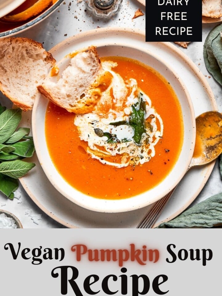 Pumpkin soup made with coconut cream sitting on a table next to sliced rustic bread.