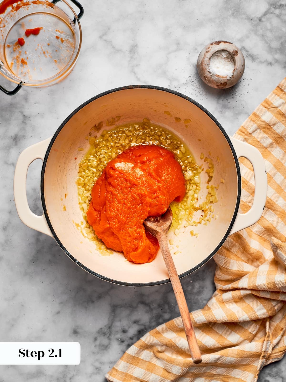 Pumpkin puree being stirred into the pot as the soup starts to take shape with spices.