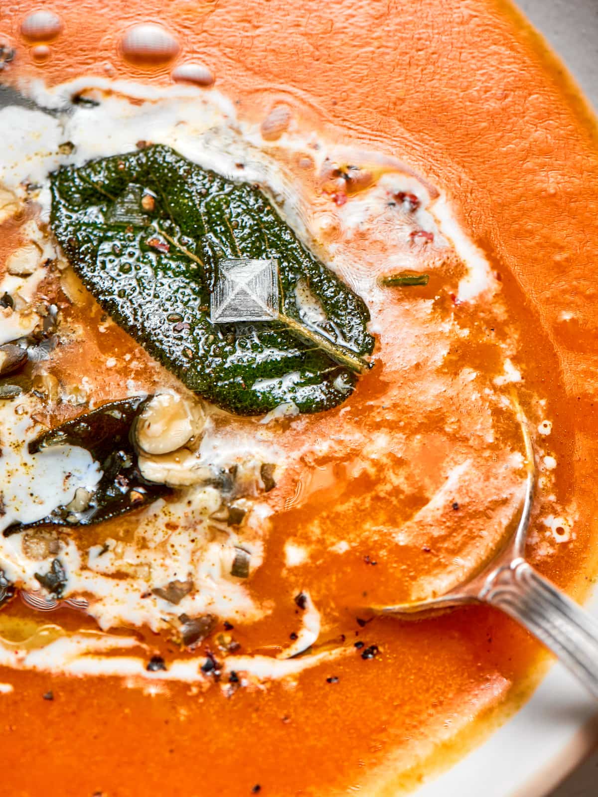 Spoon entering the bowl reveals the thick, comforting consistency of the warm pumpkin soup.