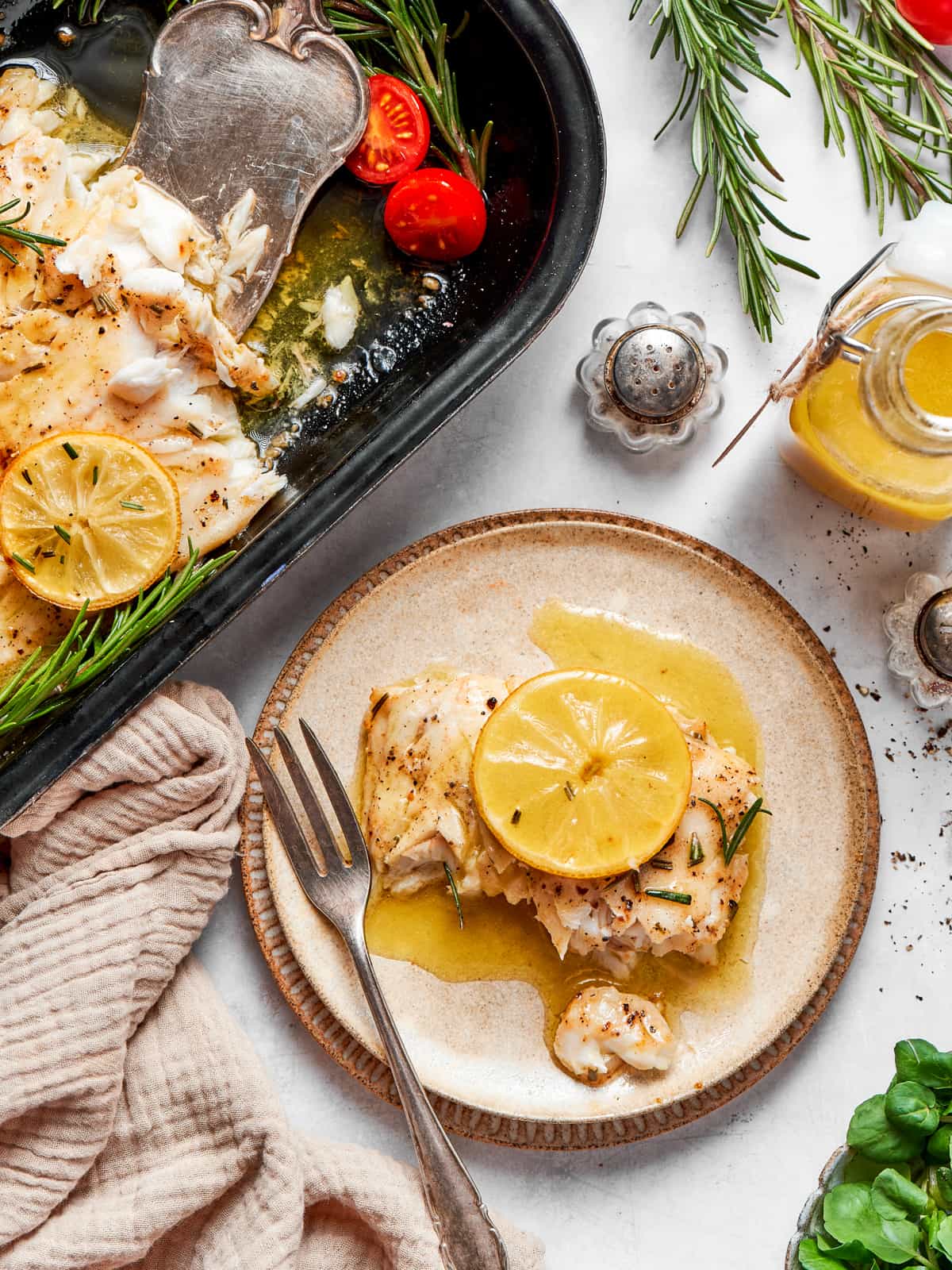 Plated baked halibut topped with lemon slice and champagne vinaigrette.