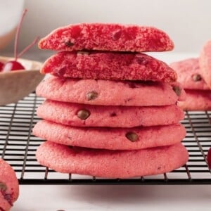 Cherry chocolate chip cookies on rack with one cookie broken open.