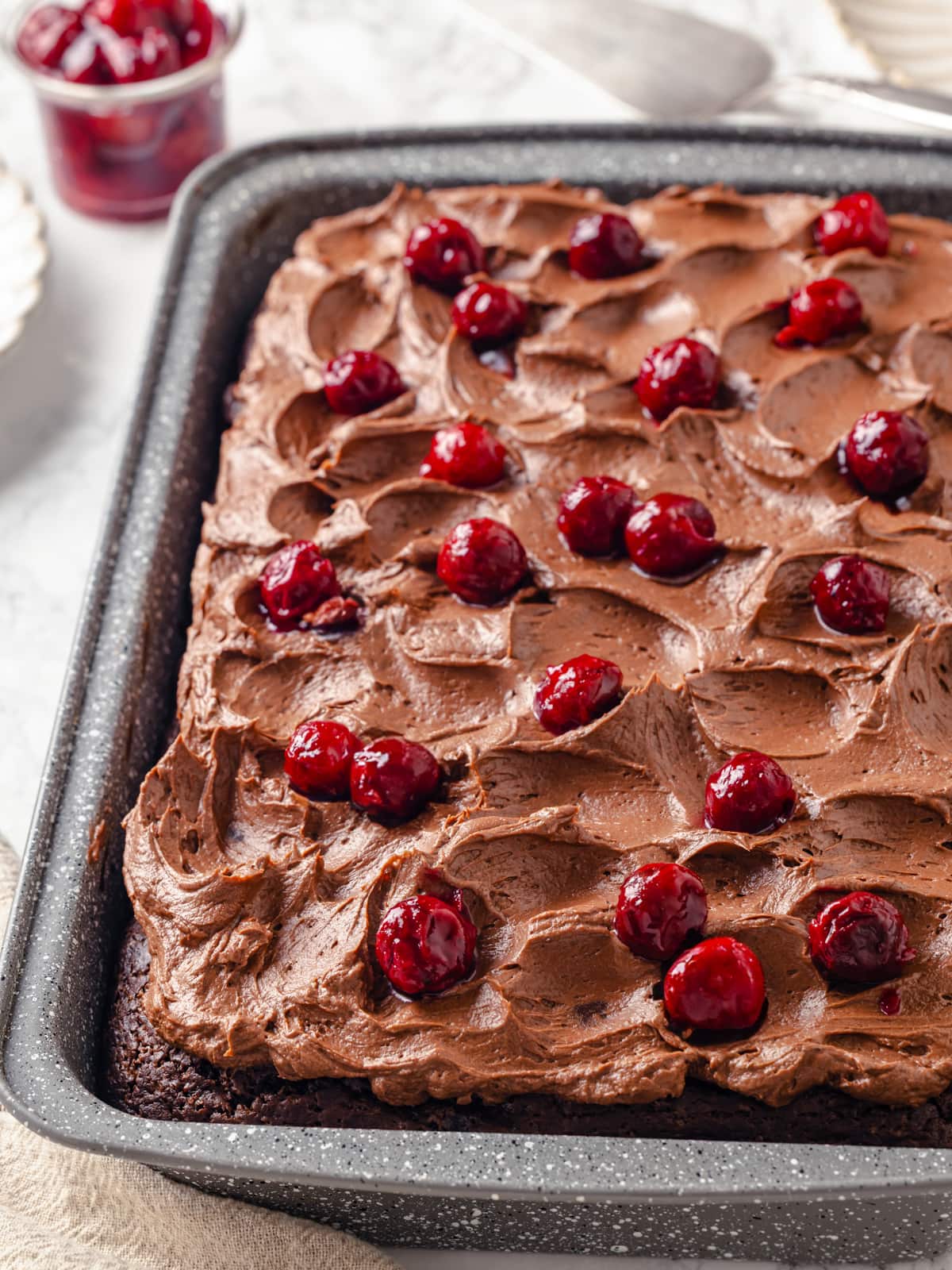 Chocolate cherry cake topped with generous cherry pie filling and soft swirled chocolate frosting.
