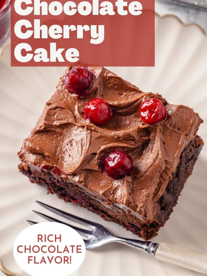 Square slice of soft chocolate cherry cake with fluffy chocolate buttercream and cherries on top.
