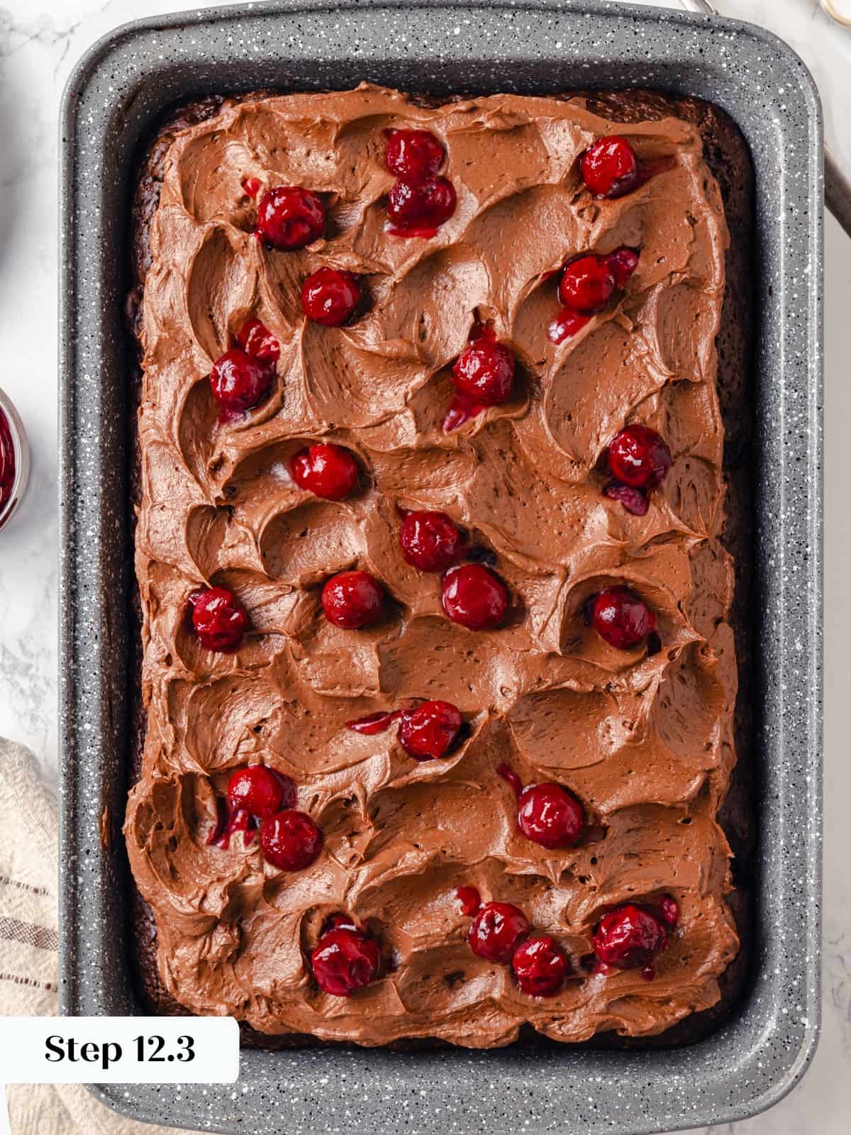 Cherries gently spread over chocolate cream cheese frosting on finished cake.