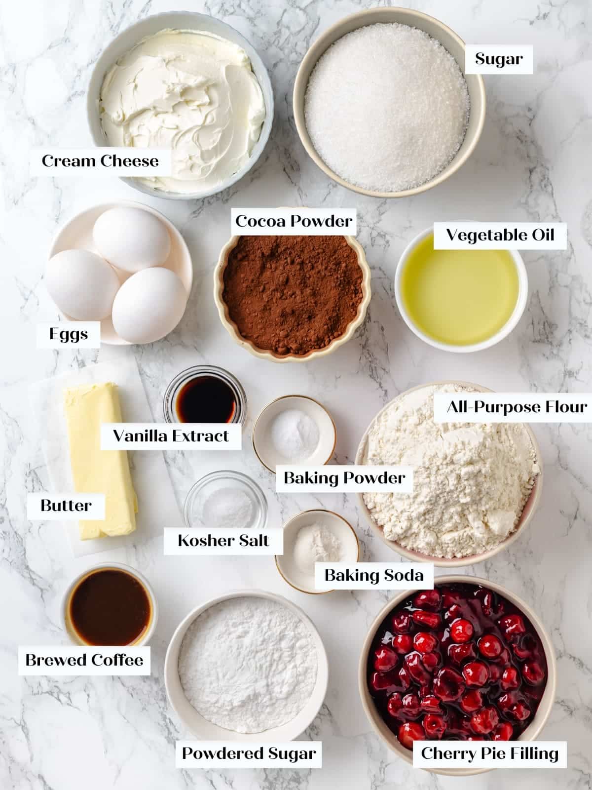 Measured chocolate cherry cake ingredients arranged on kitchen countertop.