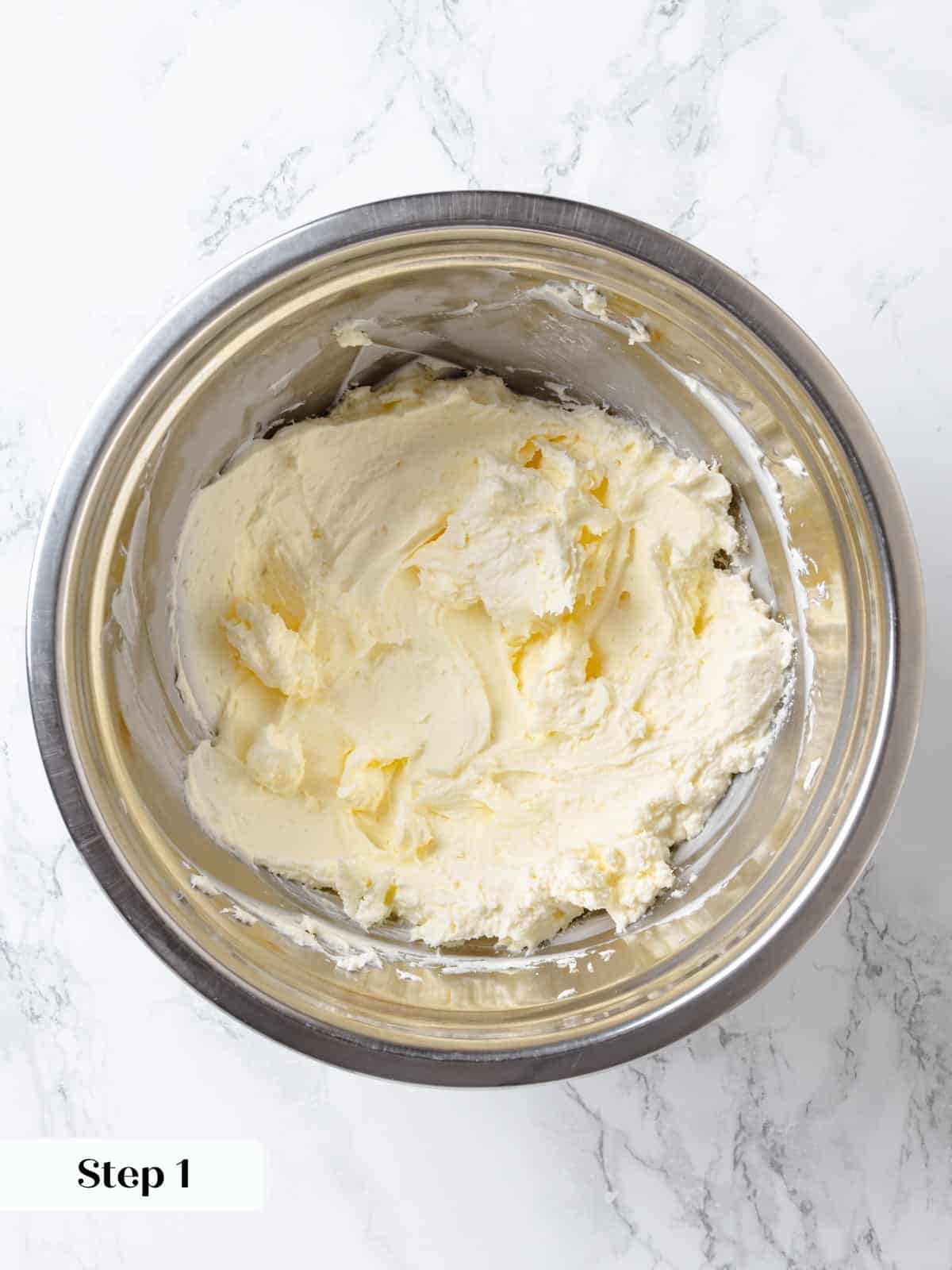 Cream cheese and butter being mixed together until smooth for chocolate frosting.