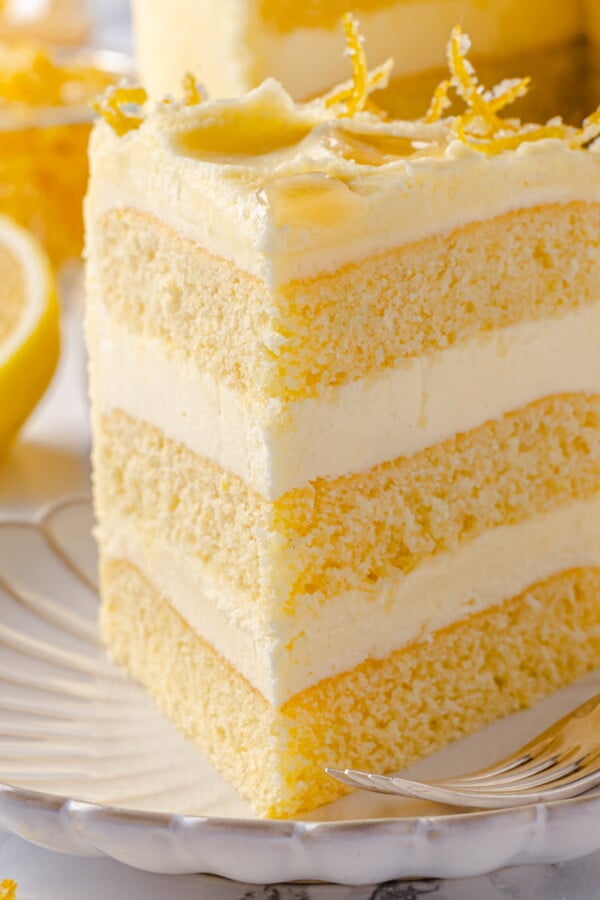 Lemon cake slice served on scalloped plate with smooth buttercream and soft crumb.