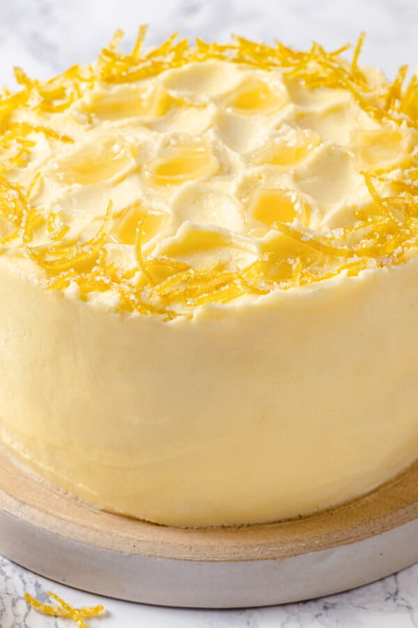 Cake topped with lemon Swiss meringue buttercream and fresh lemon peel garnish.