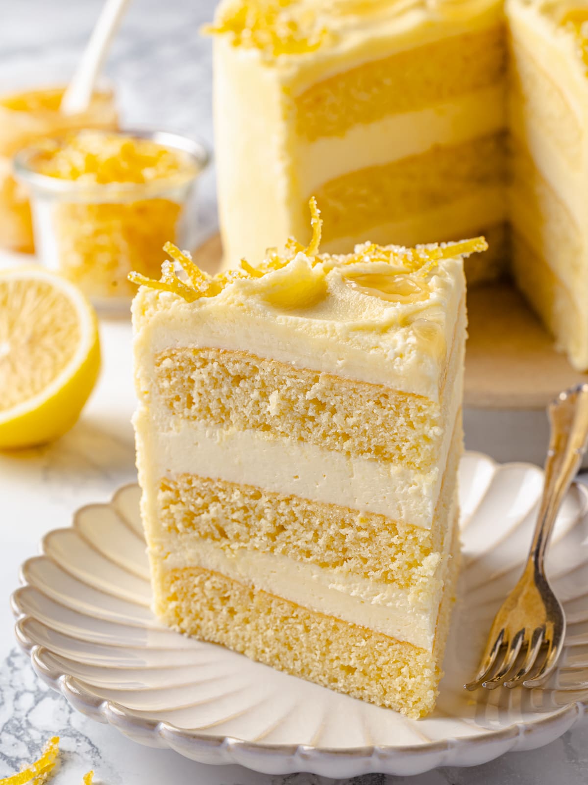 Slice of layered lemon cake showing thick layers of lemon Swiss meringue buttercream.