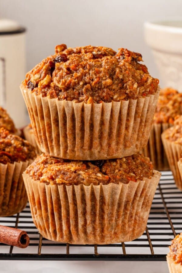 Whole grain morning glory muffins stacked together with cinnamon sticks alongside them.